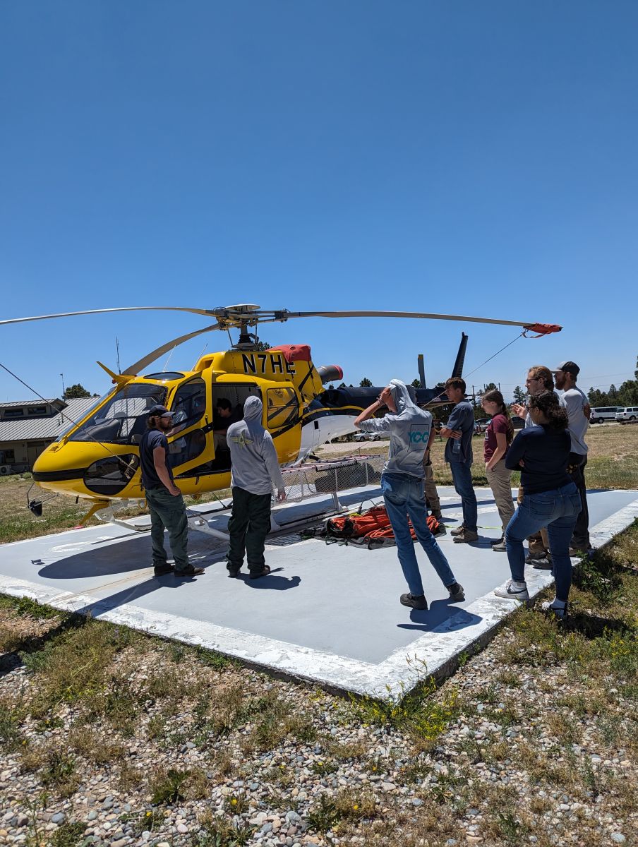 YCC crew around a yellow helicopter (field visit)