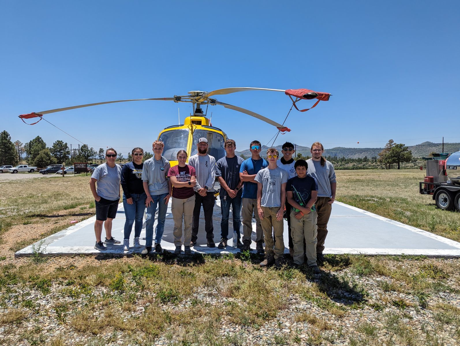 Group photo in front of a yellow helicopter