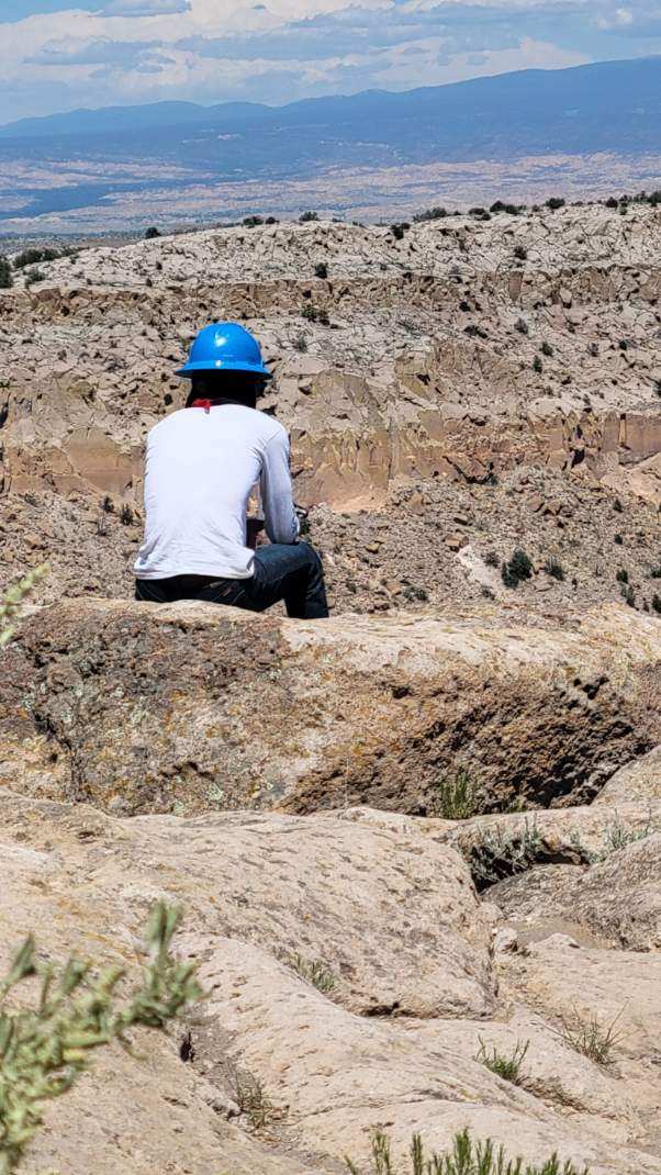 YCC member sitting on a rock, overlooking canyon views